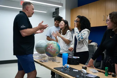 Jeff Gillis talking to a group in front of Earth and Moon globes